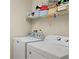 Laundry room equipped with a modern washer and dryer and a storage shelf at 15014 Arbor Hollow Dr, Odessa, FL 33556