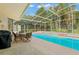 Enclosed pool area with a screened-in lanai, a dining set, and mature trees at 15014 Arbor Hollow Dr, Odessa, FL 33556