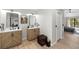 Modern bathroom with double sinks, wood cabinetry, decorative mirrors, and a view to the bedroom at 17557 Fairmeadow Dr, Tampa, FL 33647
