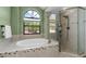 Bright bathroom showcasing a garden tub, glass-enclosed shower, and large arched window at 17557 Fairmeadow Dr, Tampa, FL 33647