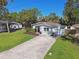 Single-story home with a concrete driveway, green lawn, and lush, mature trees at 1775 Michigan Ne Ave, St Petersburg, FL 33703