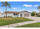 Charming single-story home showcasing a well-maintained lawn, neutral exterior, and a welcoming two-car garage at 2214 Wilshire Dr, Dunedin, FL 34698
