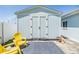 A backyard shed with double doors, a rug, yellow chairs, and an outdoor stool at 2808 W Lake Ave, Tampa, FL 33607