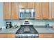 Close-up of a kitchen featuring a gas range, microwave, stainless steel backsplash, and light wood cabinetry at 308 Manns Harbor Dr, Apollo Beach, FL 33572