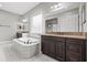 Elegant bathroom with soaking tub, granite counters, dual sinks, and walk-in shower at 32203 Wenlock Loop, Wesley Chapel, FL 33543