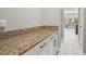 Hallway featuring a granite-topped counter space with cabinets and view into dining area at 32203 Wenlock Loop, Wesley Chapel, FL 33543