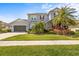 Charming two-story home with lush landscaping, gray stucco, stone accents, and red shutters at 32203 Wenlock Loop, Wesley Chapel, FL 33543