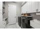 Functional laundry room with front load washer/dryer and white storage cabinets at 32203 Wenlock Loop, Wesley Chapel, FL 33543