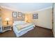 Cozy bedroom with a queen bed, decorative pictures, and carpeted floor at 36750 Us 19 N Hwy # 18-210, Palm Harbor, FL 34684