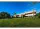 Exterior view of condo building surrounded by green lawn and mature trees at 36750 Us 19 N Hwy # 18-210, Palm Harbor, FL 34684
