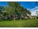 Spacious front yard with lush green lawn and mature trees surrounding the building at 36750 Us 19 N Hwy # 18-210, Palm Harbor, FL 34684