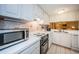 Bright kitchen with white cabinets and backsplash, alongside modern stainless appliances at 36750 Us 19 N Hwy # 18-210, Palm Harbor, FL 34684