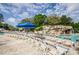 Community pool with rows of lounge chairs, blue umbrellas, and a rock waterfall feature at 36750 Us 19 N Hwy # 18-210, Palm Harbor, FL 34684