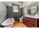 Charming bathroom featuring dark gray walls, hardwood floors, a round mirror, and a clawfoot tub at 701 S Boulevard, Tampa, FL 33606