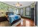 Comfortable bedroom with leaf-patterned wallpaper, hardwood floors, and a ceiling fan at 701 S Boulevard, Tampa, FL 33606