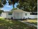 Cozy single-story home with a white lattice porch and a well-maintained lawn, surrounded by mature trees at 7202 8Th N Ave, St Petersburg, FL 33710
