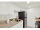 Bright kitchen featuring white cabinets, granite countertops, and modern black appliances at 7645 Sun Island S Dr # 204, South Pasadena, FL 33707