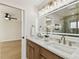 Bathroom featuring double sinks, wood cabinets, a large mirror, and neutral tiles at 9807 Bay Island Dr, Tampa, FL 33615