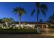 One-story home with a red tile roof, a three-car garage, lush landscaping, and outdoor lighting at 9807 Bay Island Dr, Tampa, FL 33615