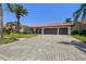 Charming single-story home with a red tile roof, a three-car garage, lush landscaping, and a paver driveway at 9807 Bay Island Dr, Tampa, FL 33615