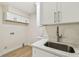 A close up of a laundry room sink and cabinet features white cabinets and wood floors at 9807 Bay Island Dr, Tampa, FL 33615