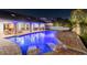 Inviting pool illuminated at night, featuring submerged lounge chairs and a covered patio with dining and seating areas at 9807 Bay Island Dr, Tampa, FL 33615