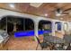 Outdoor patio features an outdoor kitchen, dining table, pool and lake views at night at 9807 Bay Island Dr, Tampa, FL 33615