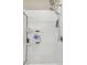 Bright bathroom with a shower featuring white tiled walls, modern fixtures, and convenient shelving at 11638 Palmetto Pine St, Riverview, FL 33569