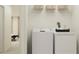 Bright laundry room with white washer and dryer and overhead shelving with woven baskets at 12751 Crystal Jade Way, Parrish, FL 34219