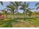 Serene backyard features lush green grass, mature trees, a white picket fence, and a picturesque pond view at 1612 Cabbage Key Dr, Ruskin, FL 33570
