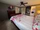 Cozy bedroom with a ceiling fan, large bed with floral bedding, and dark furniture at 2331 Belleair Rd # 904, Clearwater, FL 33764