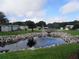 Scenic view of a pond with a fountain surrounded by rocks and landscaping, enhancing the community's natural beauty at 2331 Belleair Rd # 904, Clearwater, FL 33764