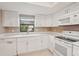 Bright kitchen featuring white cabinets, modern appliances, and a window providing natural light at 2529 Lancaster Dr, Sun City Center, FL 33573