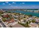A high aerial shot shows a light-blue home surrounded by community residences with a bay view in the background at 340 83Rd Ave, St Pete Beach, FL 33706