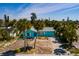 An aerial view of a light blue single story home surrounded by mature palm trees, sunny skies, and lush landscaping at 340 83Rd Ave, St Pete Beach, FL 33706