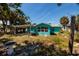 Backyard view of a quaint turquoise house with a carport and a bird bath, surrounded by lush greenery at 340 83Rd Ave, St Pete Beach, FL 33706