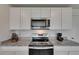 Modern kitchen features white cabinets, granite countertops, and stainless steel appliances at 35260 Spruce Knob Ct, Dade City, FL 33525