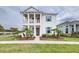 Inviting two-story home featuring a charming front porch and beautifully landscaped front yard with palm trees at 3706 Front Park Dr, Wesley Chapel, FL 33543