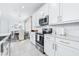 Modern kitchen with white cabinets, stainless appliances and stone countertops open to dining at 3706 Front Park Dr, Wesley Chapel, FL 33543