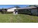 Backyard featuring lush lawn, manicured hedges, sunroom and patio with rocking chairs at 40 Gretchen Ct, Oldsmar, FL 34677