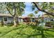 Spacious backyard with lush artificial grass, mature trees, patio, and a charming tiki-style hammock swing at 4414 W El Prado Blvd, Tampa, FL 33629