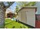 Backyard view featuring artificial turf, mature trees, and a shed near a tiki bar with seating at 4414 W El Prado Blvd, Tampa, FL 33629