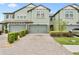 Two-story townhome with a brick paver driveway and manicured landscaping at 4663 Almada Ln, Wesley Chapel, FL 33543