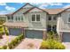 Two-story townhome with brick paver driveway, gray garage doors, and manicured landscaping at 4663 Almada Ln, Wesley Chapel, FL 33543