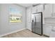 Bright eat-in kitchen featuring a stainless steel refrigerator, white cabinets, and a window with a neighborhood view at 4663 Almada Ln, Wesley Chapel, FL 33543