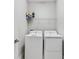 Functional laundry room with white washer and dryer units and wire shelving above at 4663 Almada Ln, Wesley Chapel, FL 33543