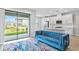 Modern open concept living room with a blue sofa, kitchen area and sliding glass doors at 4663 Almada Ln, Wesley Chapel, FL 33543