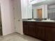 Bathroom with double vanity, brown cabinets, and gray granite countertop at 4908 Babbling Brook Ln, Wimauma, FL 33598