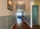 Bright hallway with wood floors leading to a sunlit living area, with stylish lighting at 4908 Babbling Brook Ln, Wimauma, FL 33598