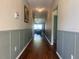 Inviting hallway with wood floors and decorative wainscoting, leading to a bright living area at 4908 Babbling Brook Ln, Wimauma, FL 33598